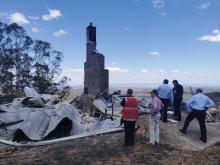 State Recovery Coordinator in front of burnt out building